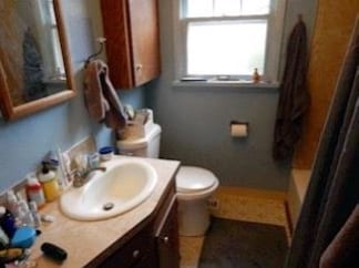 The bathroom before the remodel: a laminate-top vanity with a drop-in sink, wall cabinet over the toilet, and a cluttered counter.
